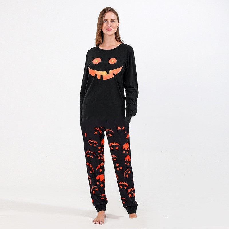 Woman modeling black pumpkin-grin pajama top paired with orange jack-o-lantern print jogger pants