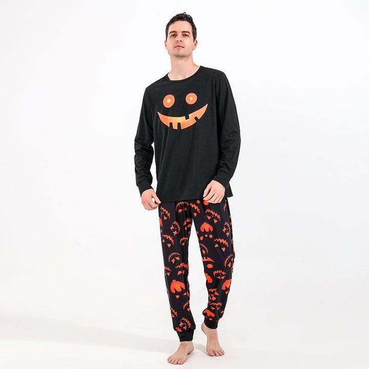 Man wearing black Halloween pajama set with glowing pumpkin smile top and printed jogger pants