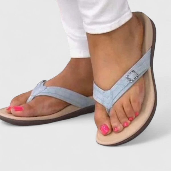 Model wearing light blue denim-style flip-flop sandals with buckle detail