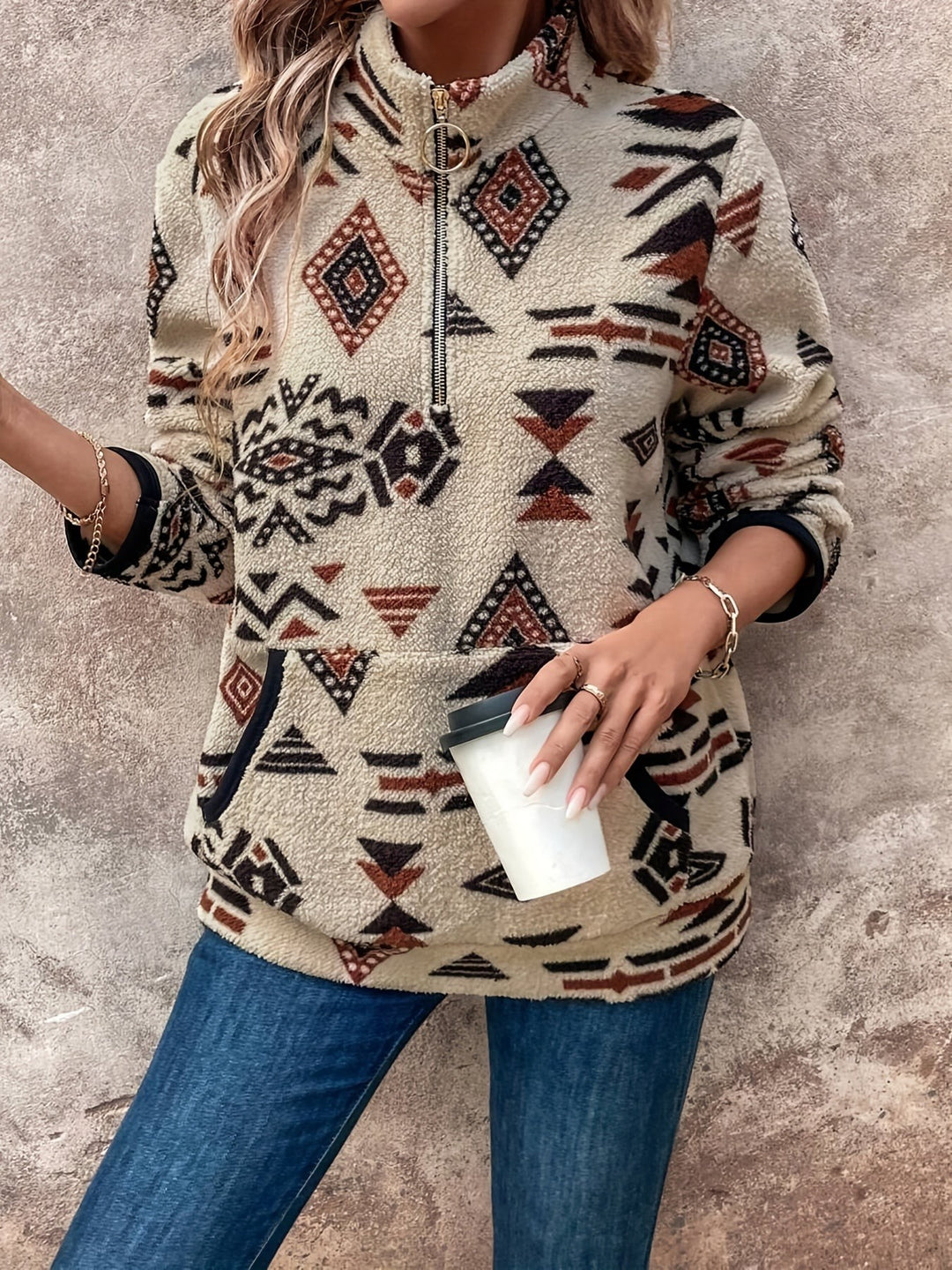 Aztec-print fleece jumper with zip collar, model holding a takeaway coffee cup