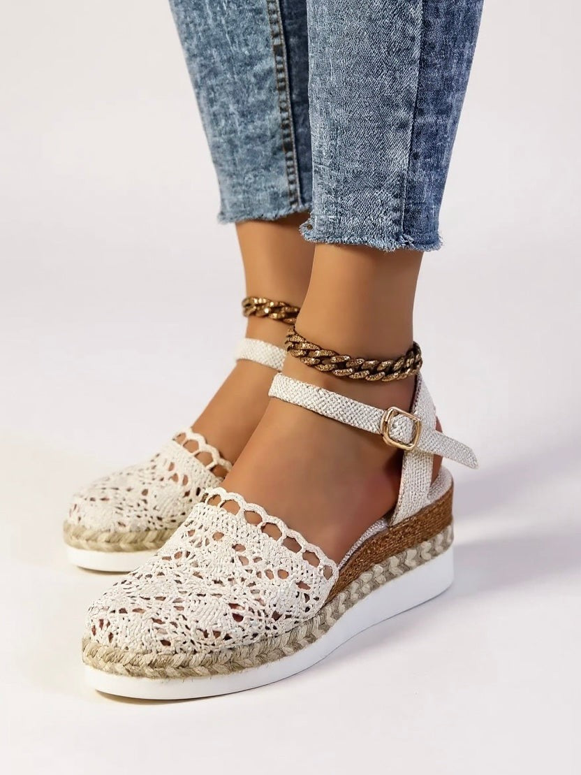 White woven wedge sandals paired with layered ankle chain jewelry
