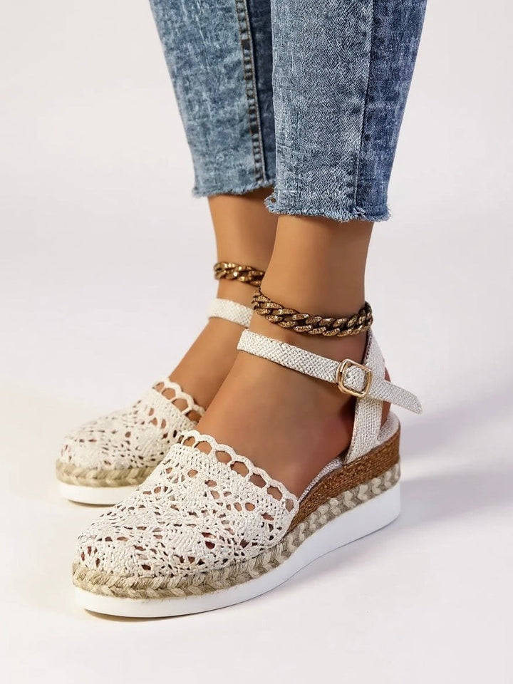 White woven wedge sandals paired with layered ankle chain jewelry