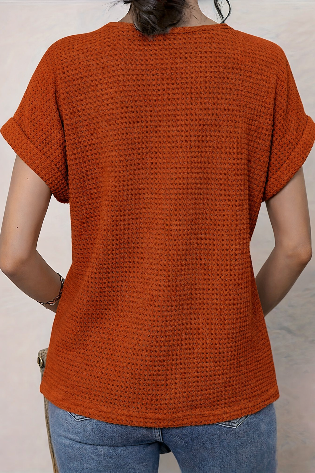 Back view of rust orange waffle-knit top with cuffed sleeves