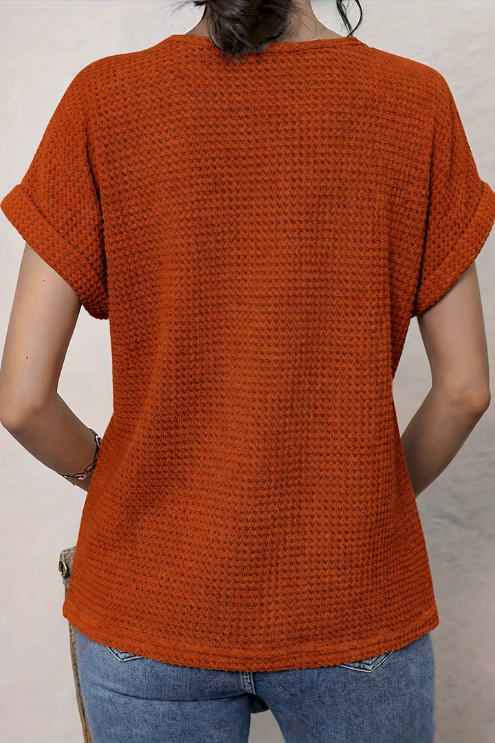 Back view of rust orange waffle-knit top with cuffed sleeves