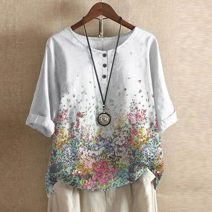White floral print blouse with cuffed half sleeves and colorful botanical design
