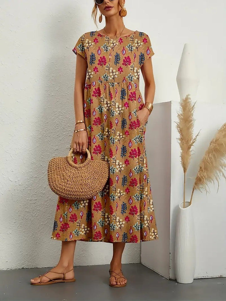 Tan botanical print midi dress paired with sandals and a straw handbag