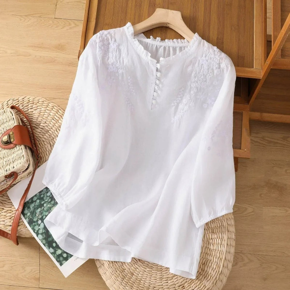White floral embroidered blouse featuring ruffled V-neck and button placket
