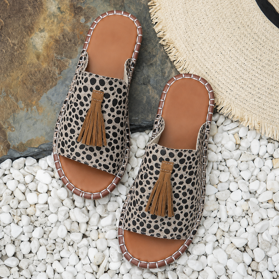 Cheetah print flat slide sandals displayed on white pebble background