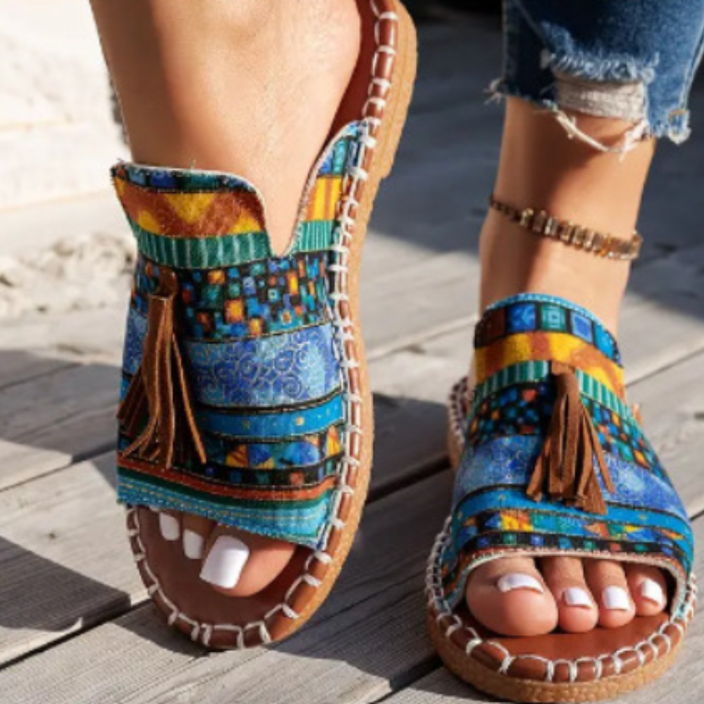 Blue tribal print flat slide sandals featuring suede tassel accent