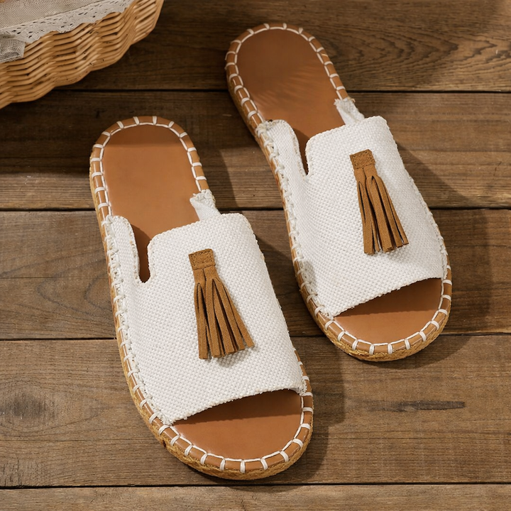 White canvas flat slide sandals with tan tassel and woven sole