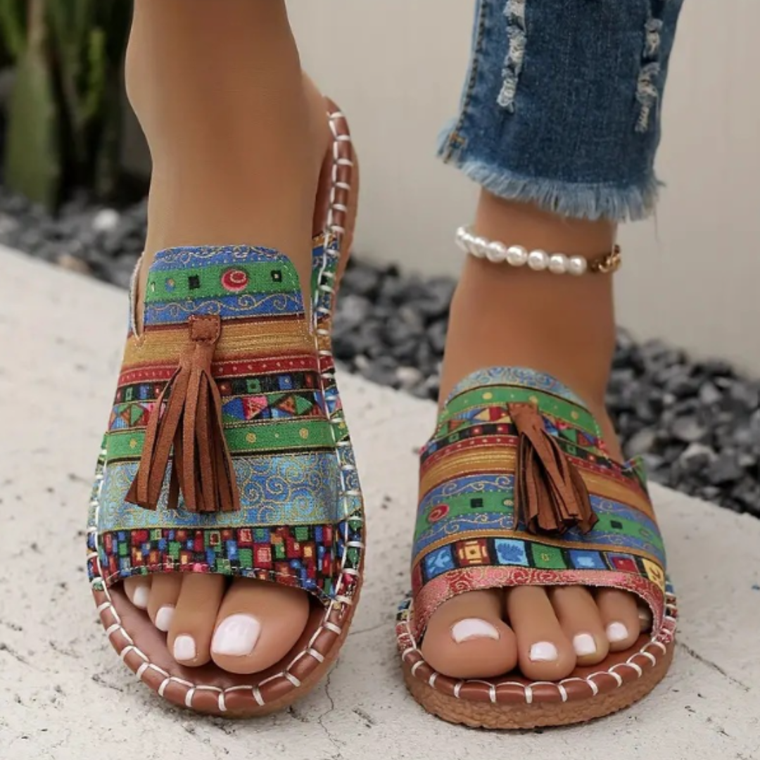 Rust tribal print flat sandals with tassel accent and ankle strap