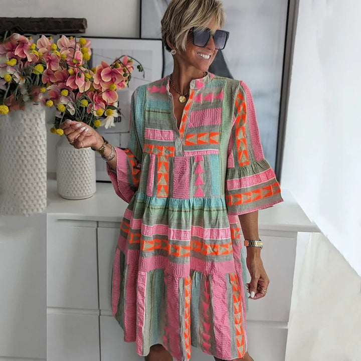 Geometric print tiered babydoll dress in pink and orange with bell sleeves