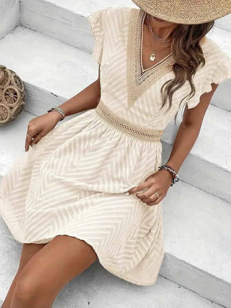 seated model wearing cream mini dress with crochet lace detailing