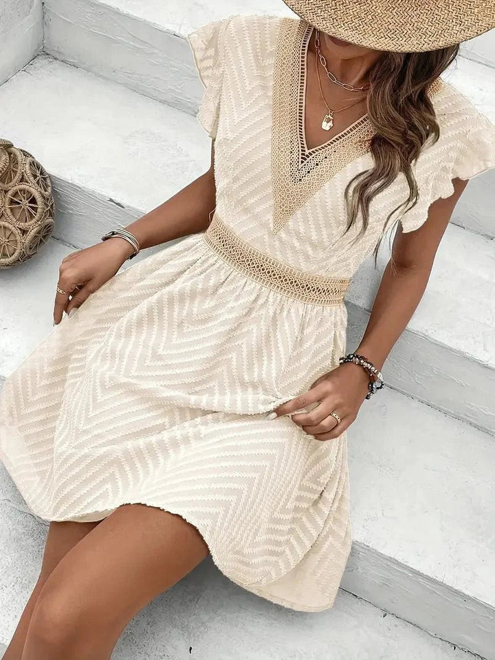 seated model wearing cream mini dress with crochet lace detailing