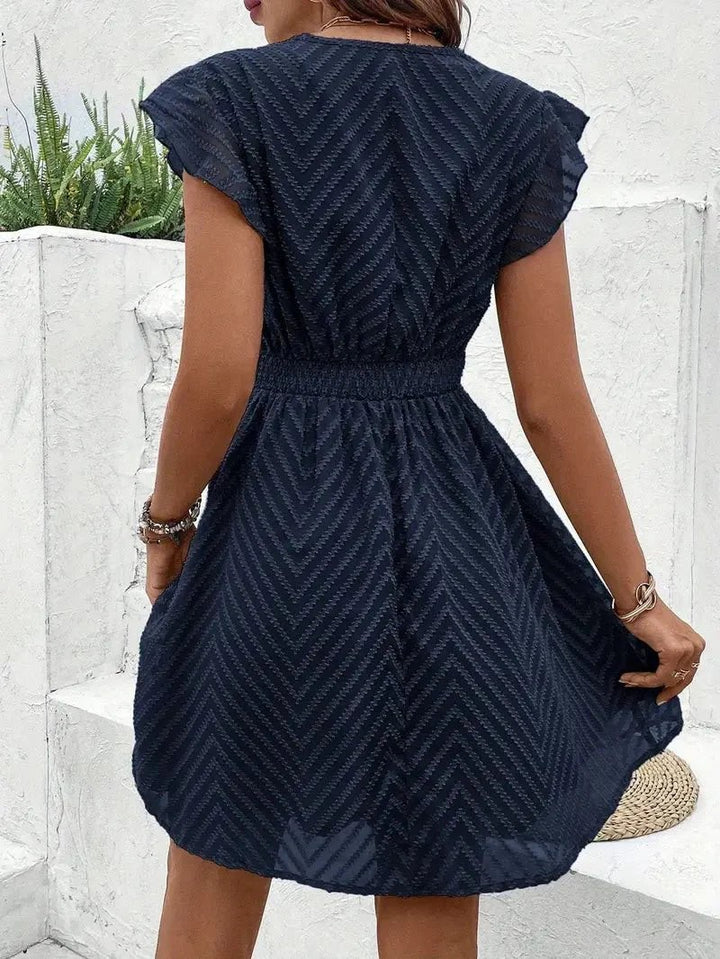 back view of navy chevron mini dress with flutter sleeves