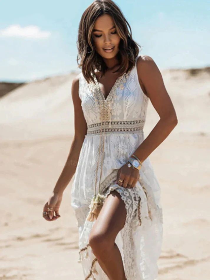 Bohemian white lace maxi dress with tasseled V-neck, model walking on sand