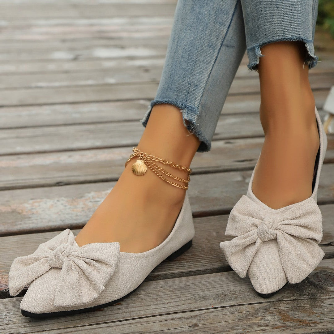 Cream suede pointed-toe flats with bow detail and gold ankle bracelet