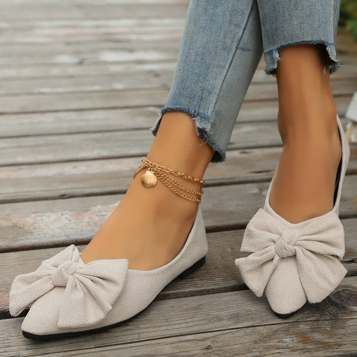 Cream suede pointed-toe flats with bow detail and gold ankle bracelet