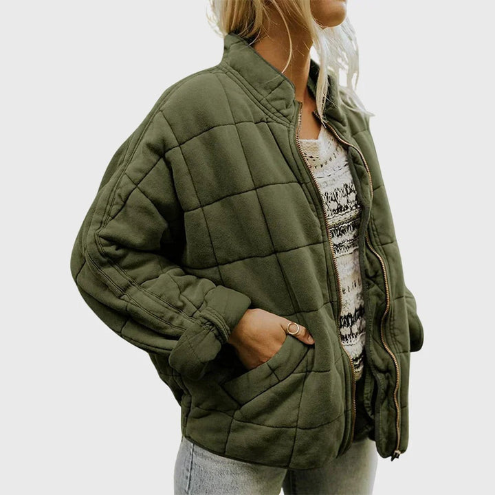Khaki green quilted puffer jacket with stand collar worn over knitted jumper