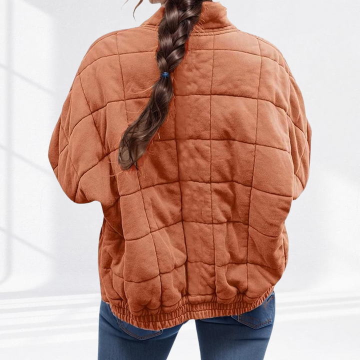 Rear view of rust orange quilted puffer jacket with ribbed waistband