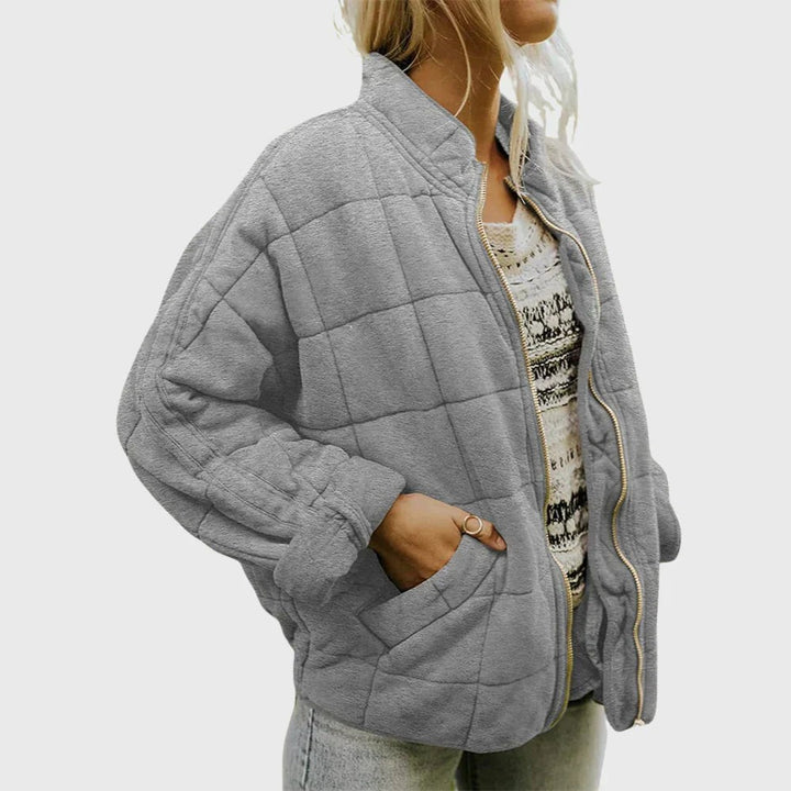 Grey quilted puffer jacket with hand tucked into side pocket