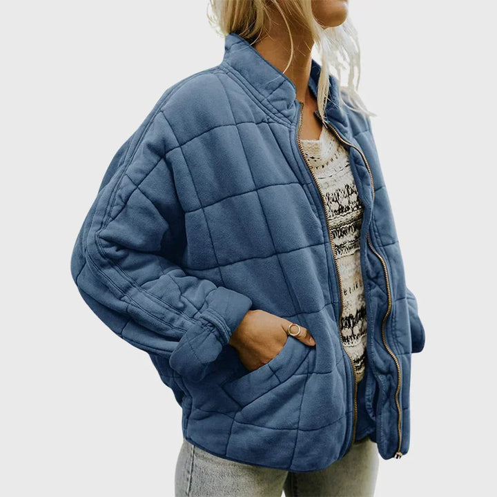 Slate blue quilted puffer jacket worn open over patterned knitwear