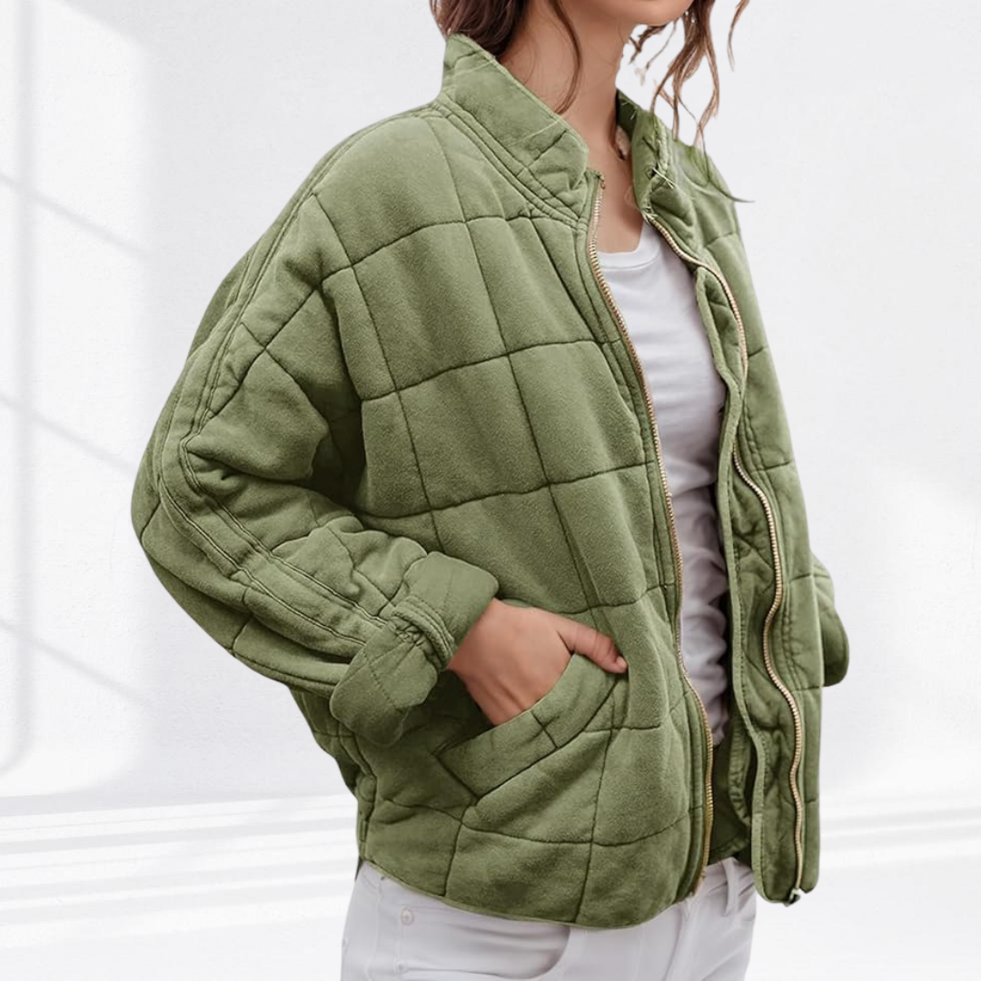 Sage green quilted puffer jacket worn over white top with hand in pocket