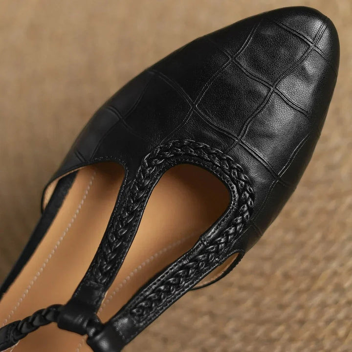 close-up of black leather flat showing braided strap and quilted toe