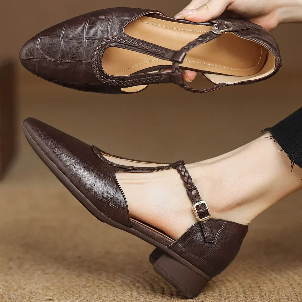 close-up of brown leather Mary Jane flats showing braided T-strap and buckle
