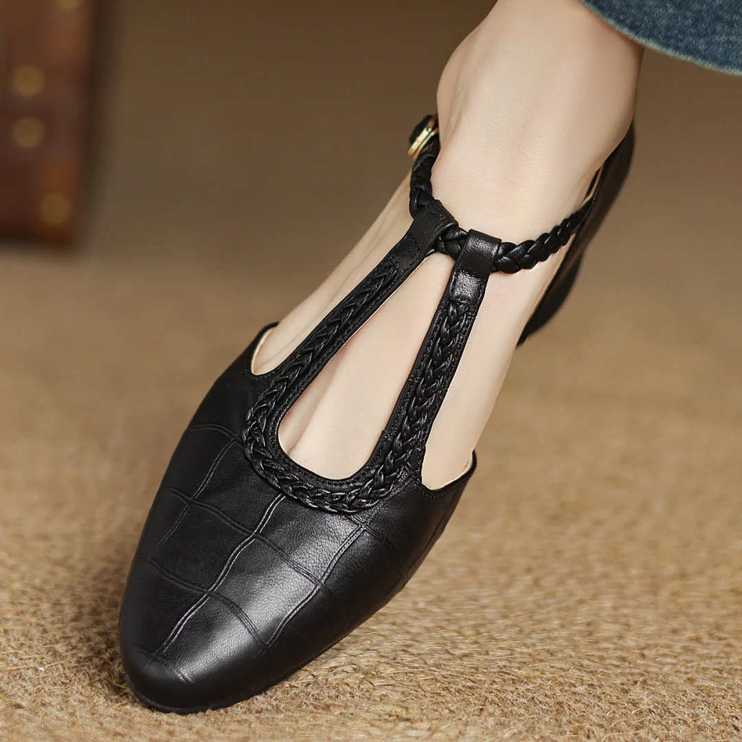 pair of black leather pointed toe flats with woven T-strap and buckle
