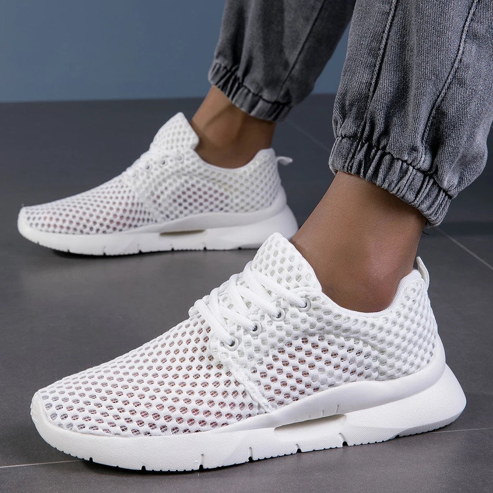 Breathable white knit sneakers worn with gray joggers, side view