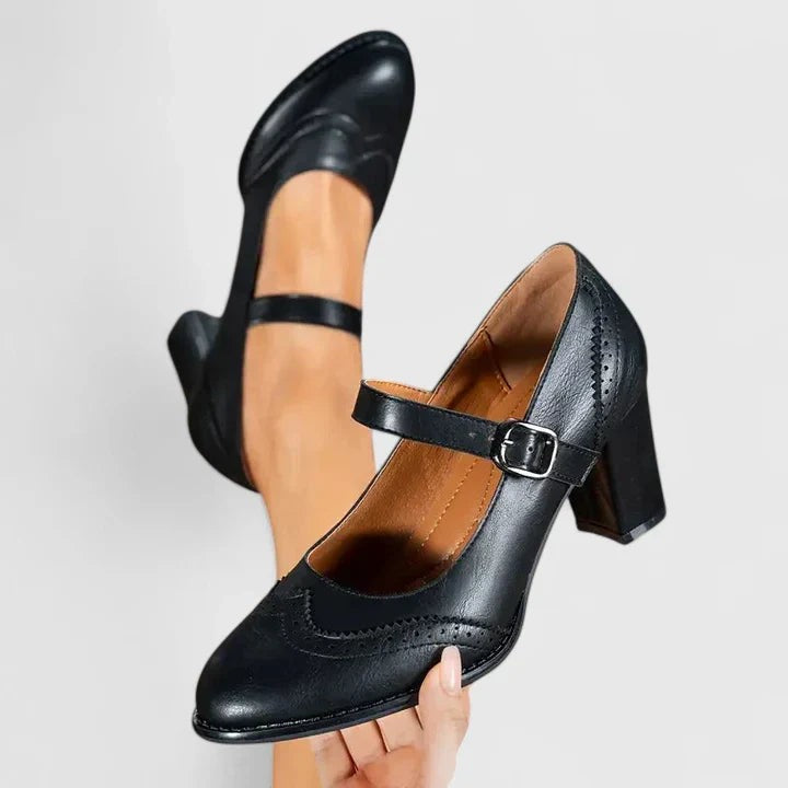 Black leather Mary Jane block heel shoe held up showing brogue toe detail