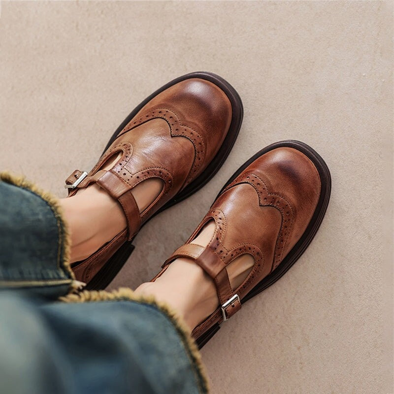 brown leather T-strap Mary Jane shoes with brogue wingtip detailing worn on feet