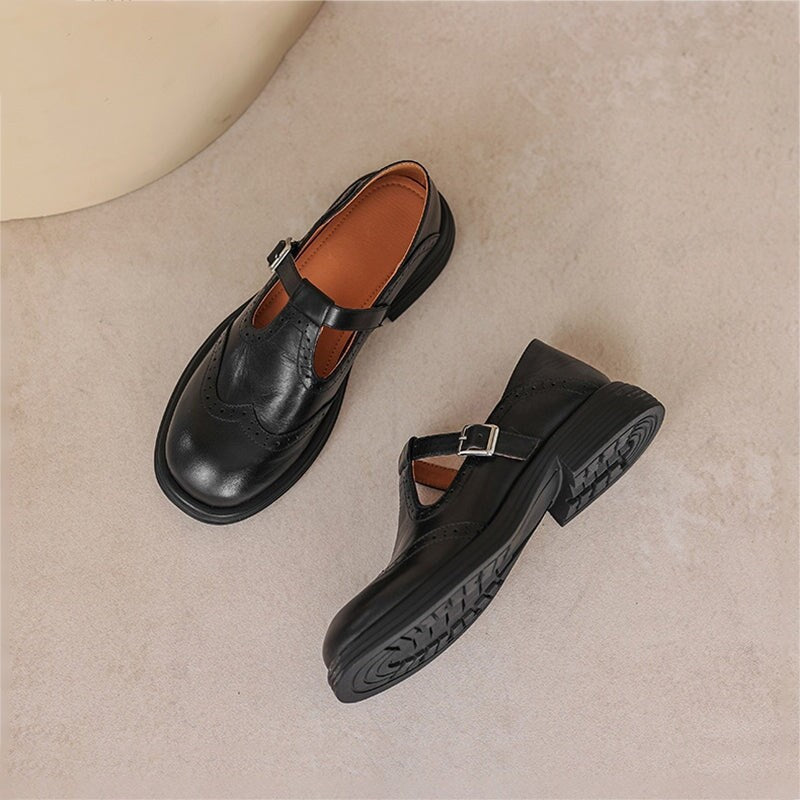 pair of black leather brogue Mary Jane shoes with buckle strap on textured floor