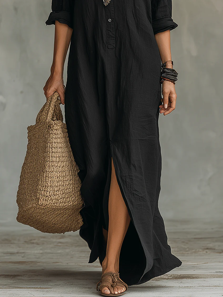Front hem detail of black maxi shirt dress with side slit and woven straw bag