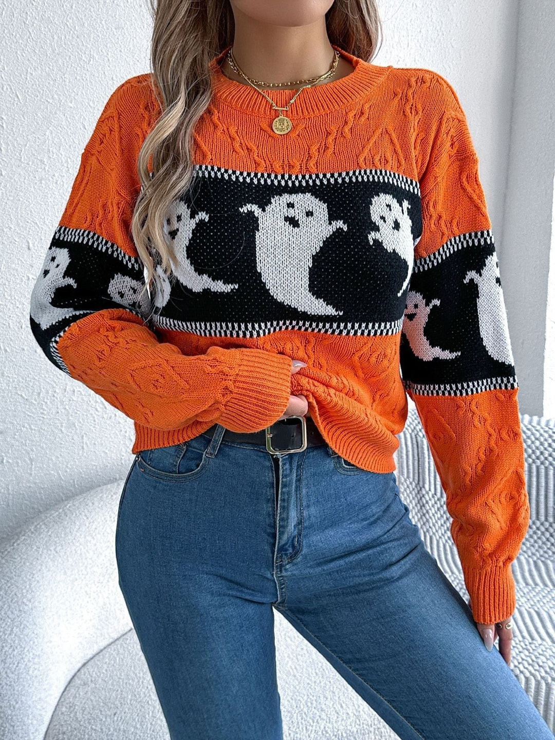 Close-up of orange ghost print sweater showing cable-knit detail and ghost motif