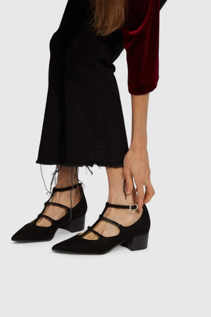 close-up of black suede T-strap heels with buckle ankle strap