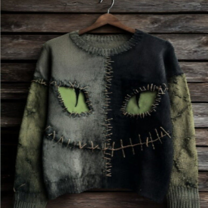 olive and black distressed sweater with stitched cat-eye monster design