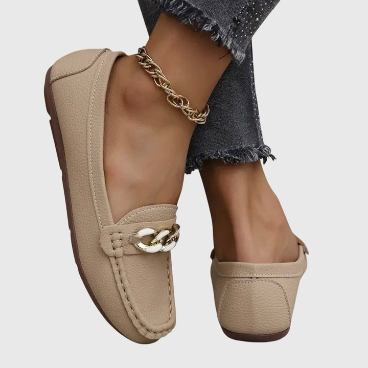 Beige leather flats with chain buckle detail, paired with gold ankle chain
