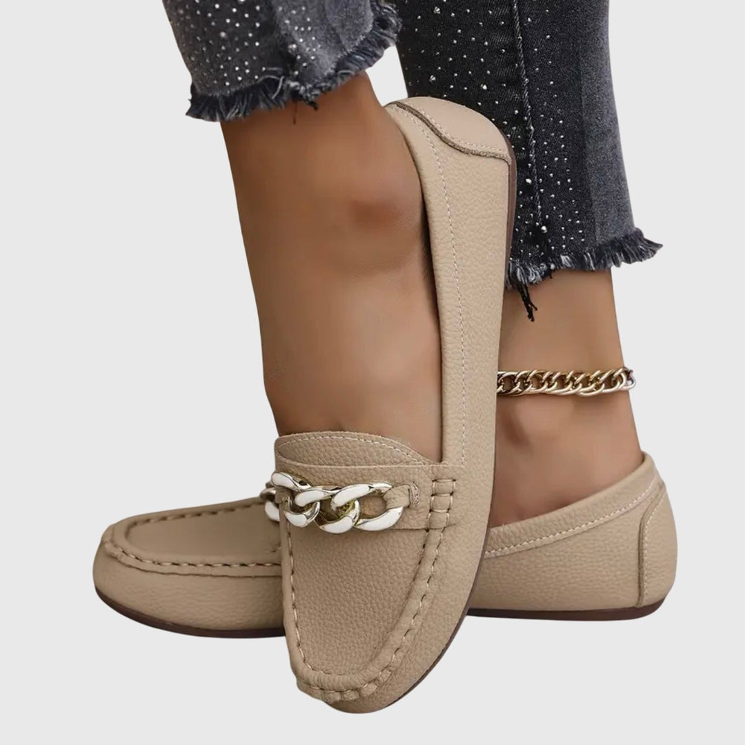 Beige leather loafers highlighting stitched moc-toe design and chain trim