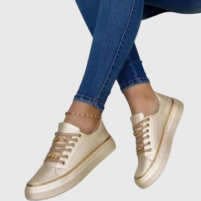 Pearl white sneakers with gold chain detail and metallic sole trim