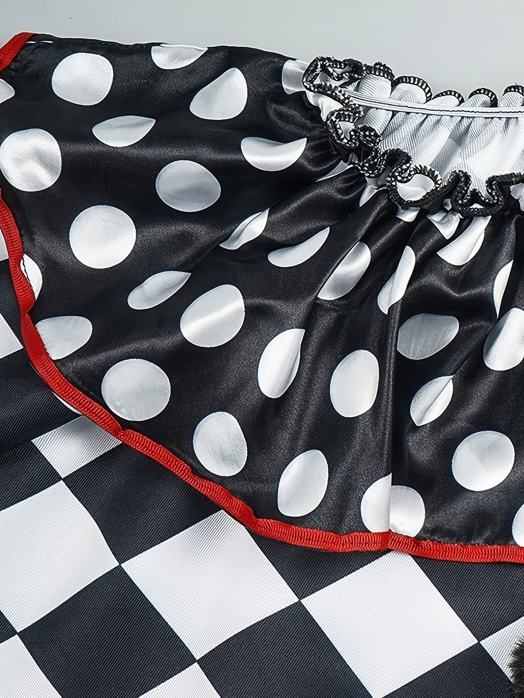 detail shot of polka-dot ruffle collar with red trim on harlequin cape