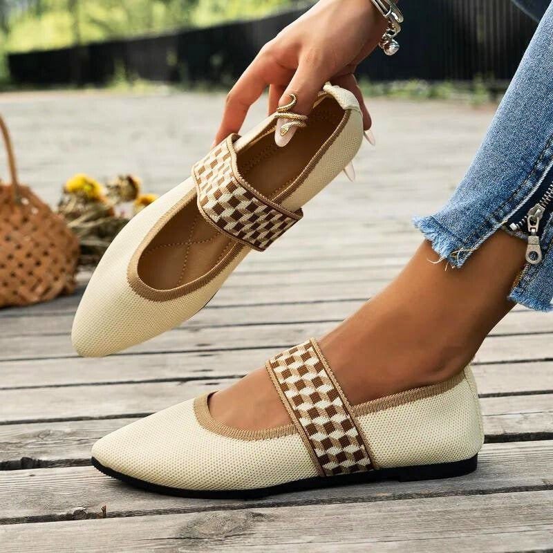 Cream knit Mary Jane flats with checkered strap, held in hand outdoors