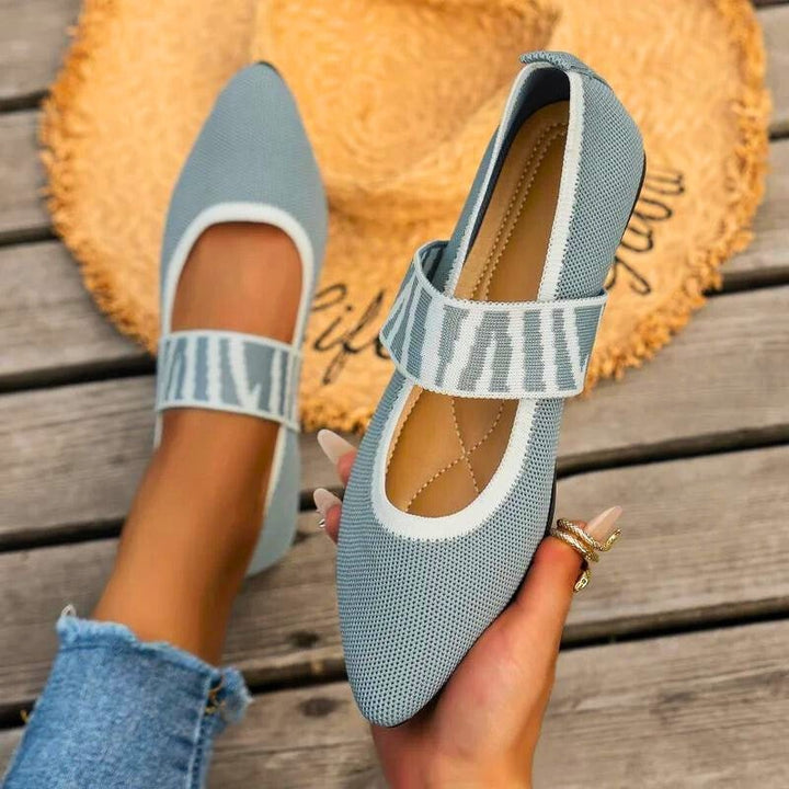 Light blue knit pointed-toe flats with striped Mary Jane strap, worn outdoors