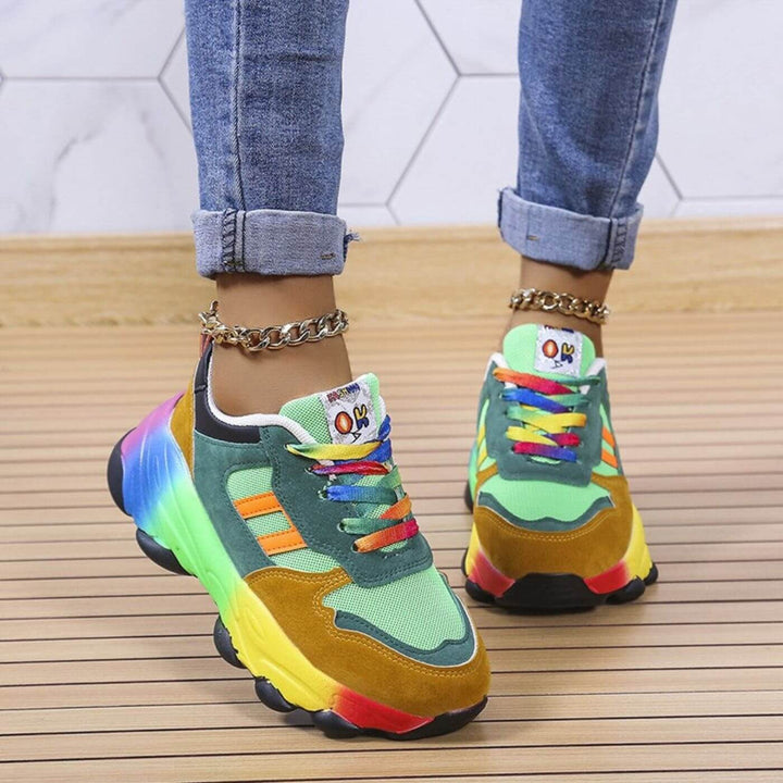 Green and tan chunky sneakers with rainbow laces, back view worn with rolled jeans