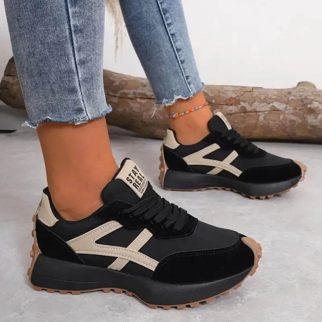 Black and beige chunky sneakers with lugged sole worn with cropped jeans