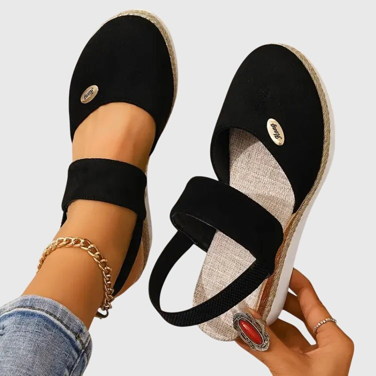 Black espadrille sandal pair with elastic straps and woven platform wedge