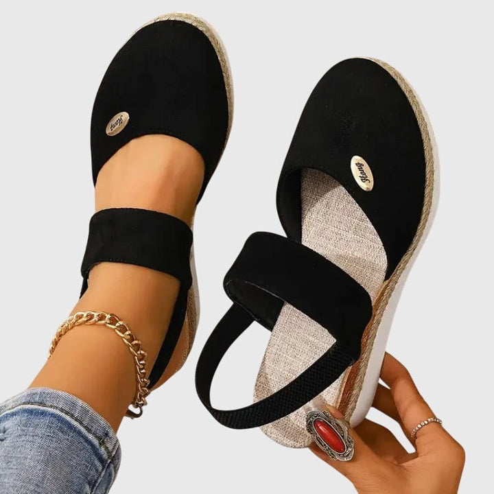Black espadrille sandal pair with elastic straps and woven platform wedge