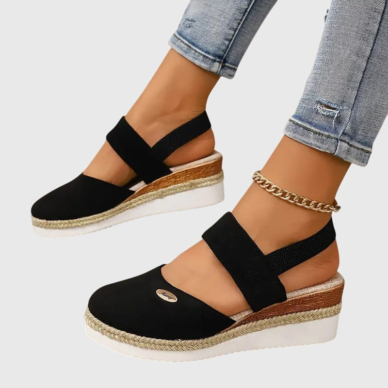 Black closed-toe wedge sandal with elastic straps and braided espadrille platform