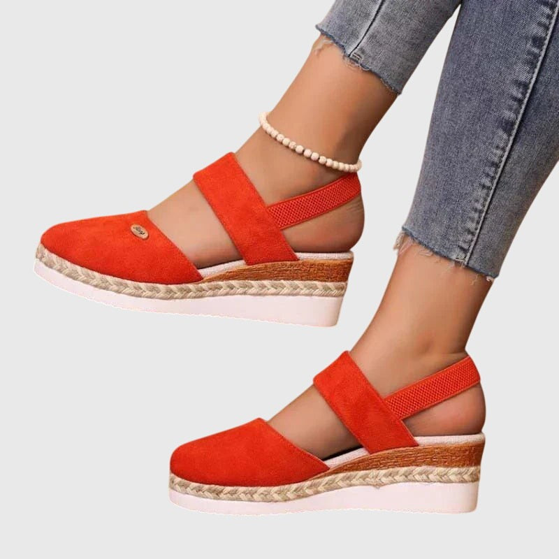 Orange suede platform sandal with crisscross elastic straps and woven wedge sole